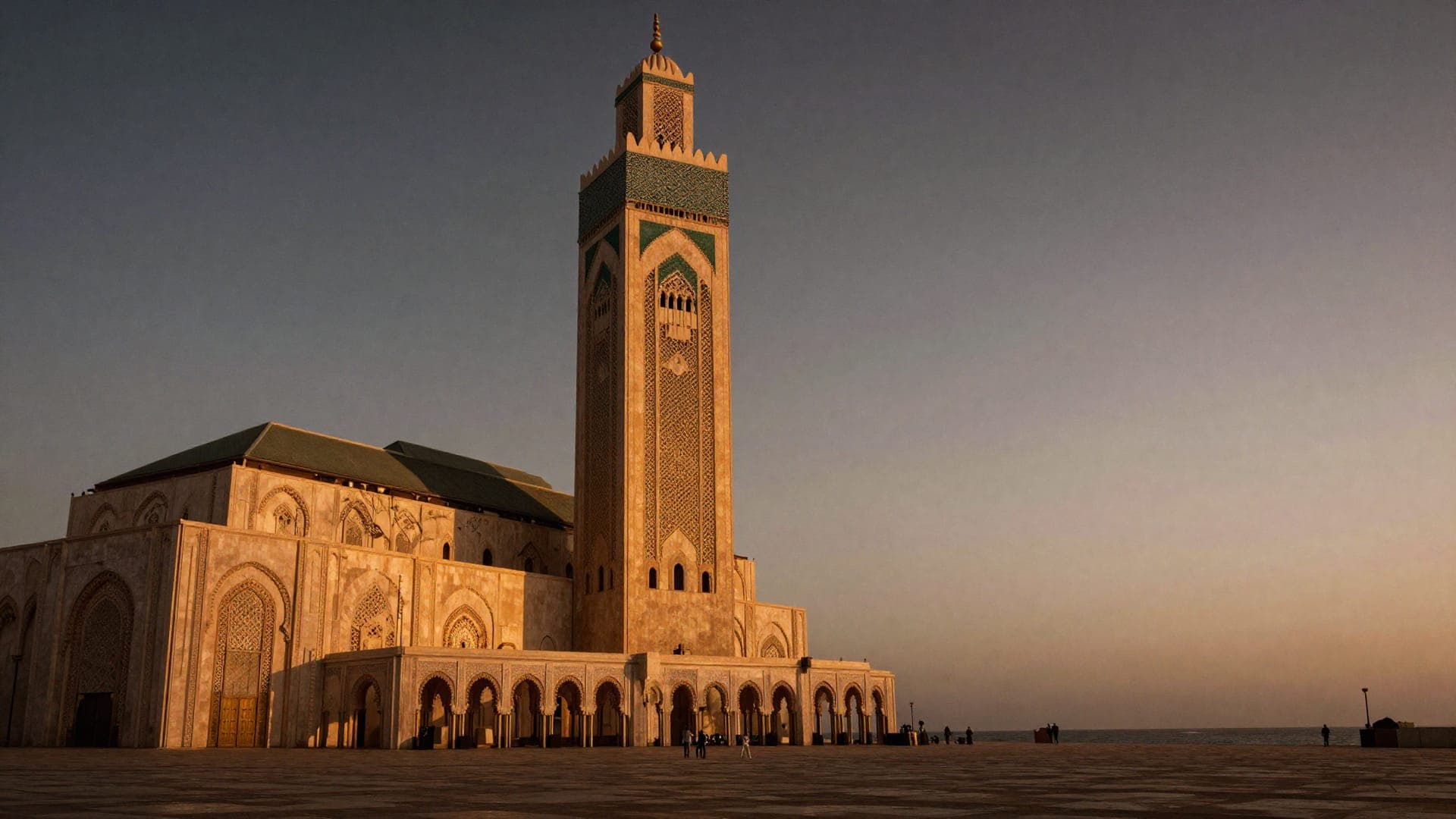 The minaret of the Hassan II Mosque towering over its ocean esplanade at dusk