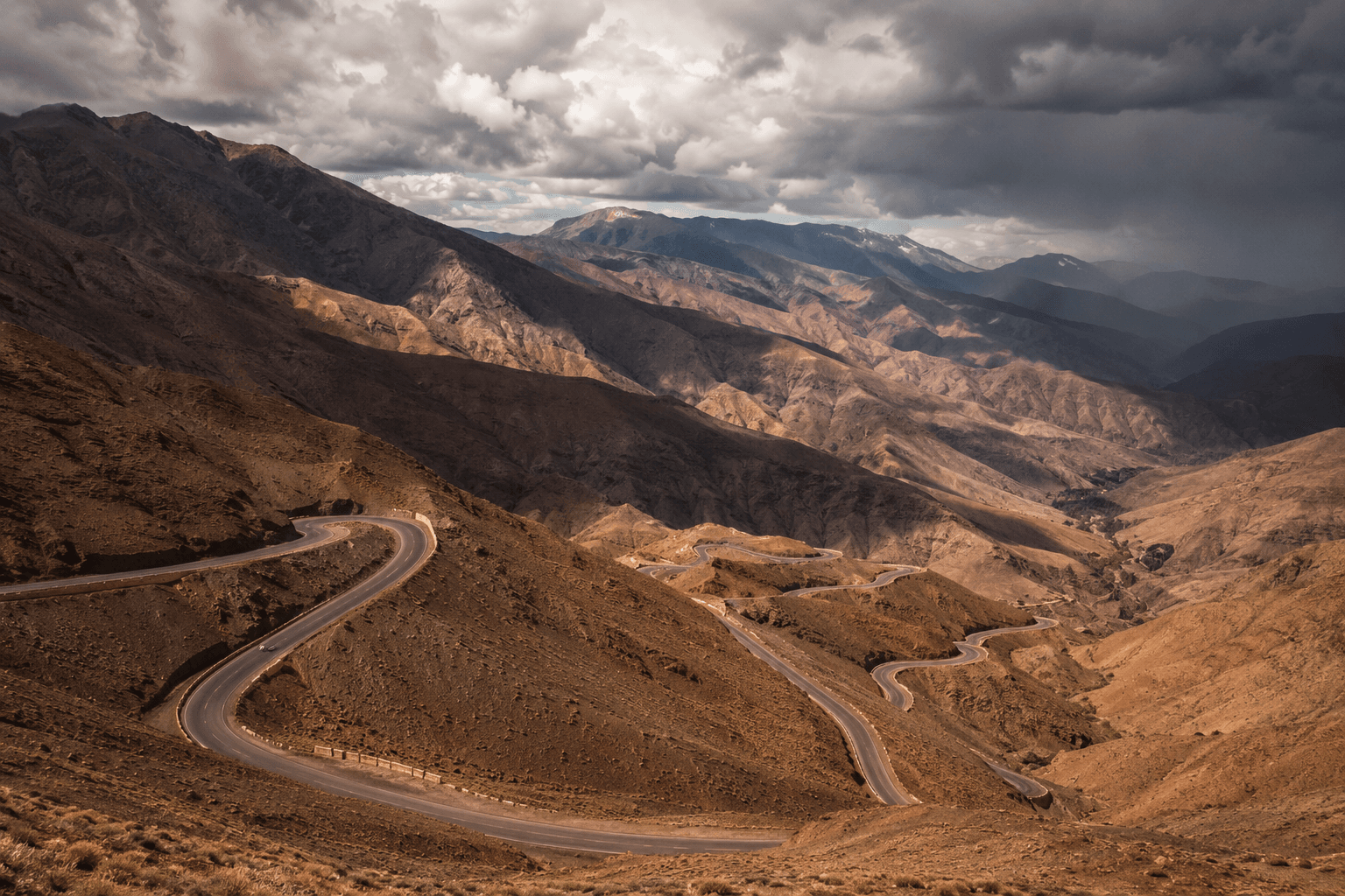 The Tizi n'Tichka road switchbacking down a bare red mountainside in the High Atlas